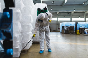 Exterminator spraying for pests in warehouse